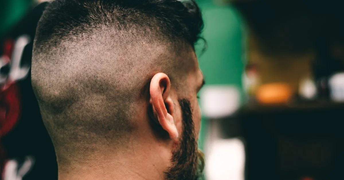 Vista trasera en primer plano de un hombre con un corte de cabello fresco en una barbería, mostrando un desvanecido marcado.