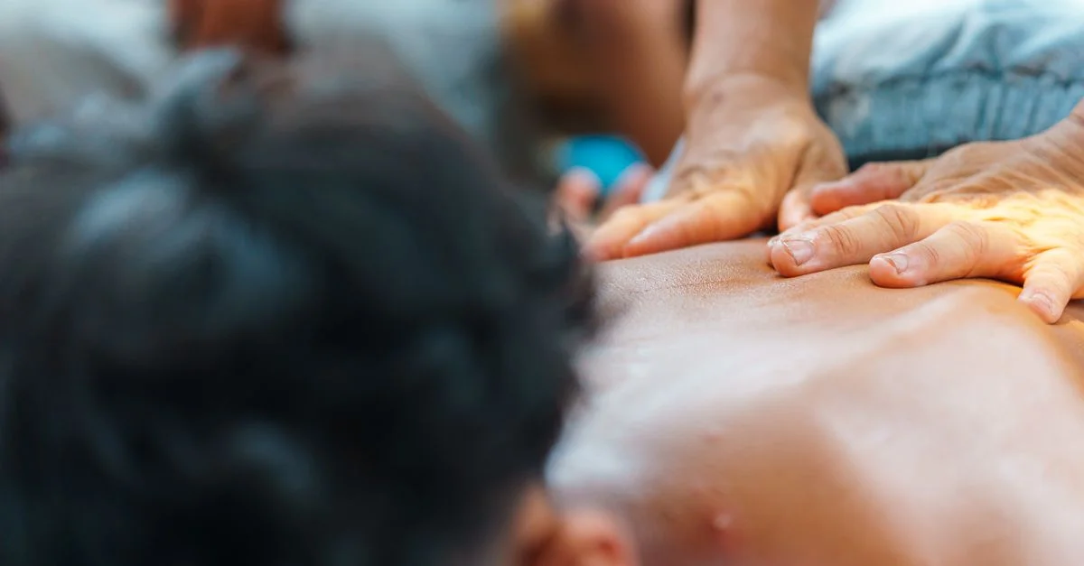 Vista en primer plano de manos realizando una sesión de terapia de masaje relajante en la espalda de una persona, promoviendo la relajación.