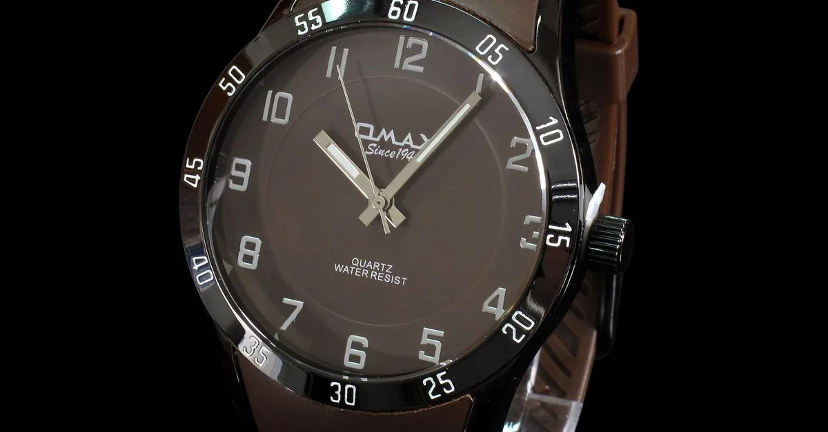 Reloj de pulsera elegante con correa de cuero marrón, diseño estilizado y marcadores de horas visibles sobre un fondo negro.