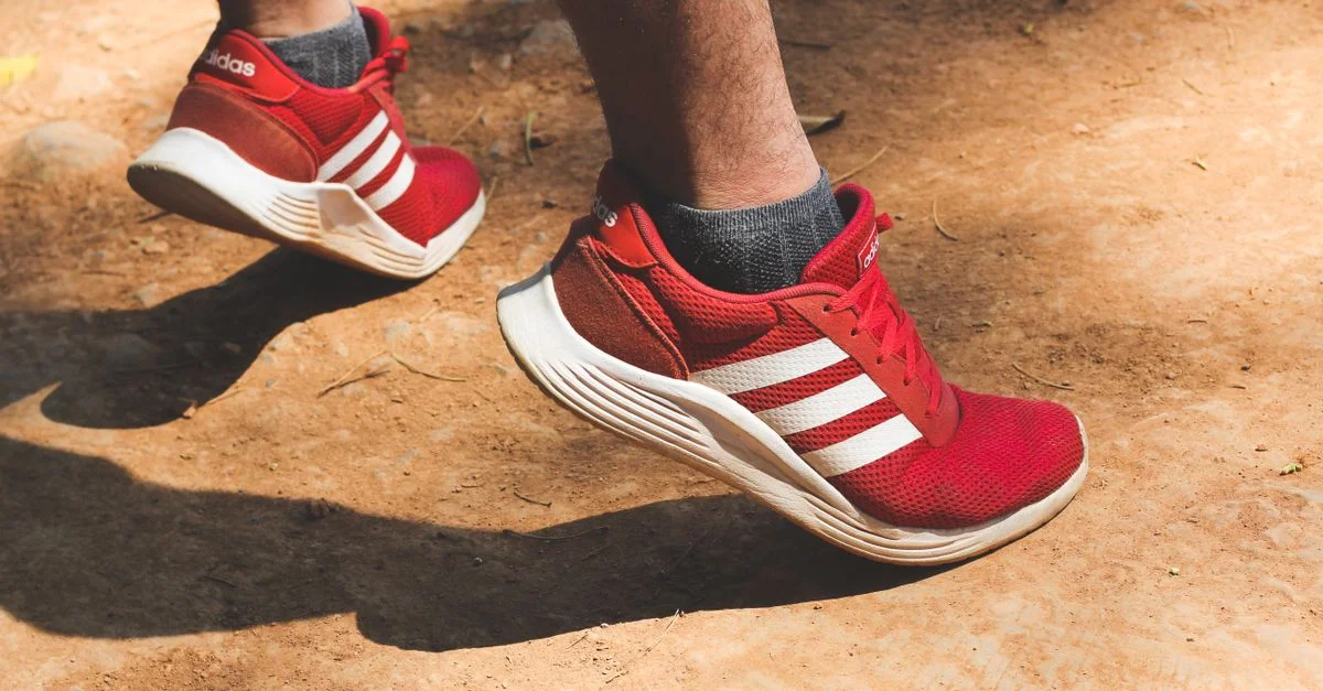 Acercamiento de zapatillas rojas en movimiento en un camino polvoriento al aire libre.