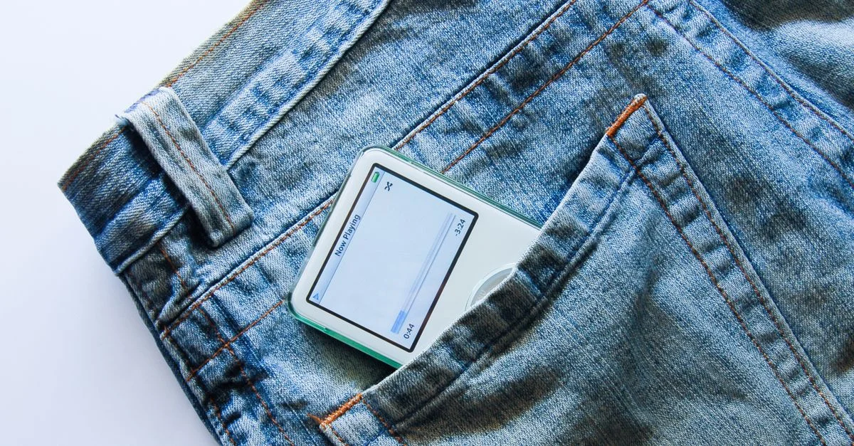 Primer plano de un reproductor de MP3 vintage parcialmente visible en un bolsillo de jeans.