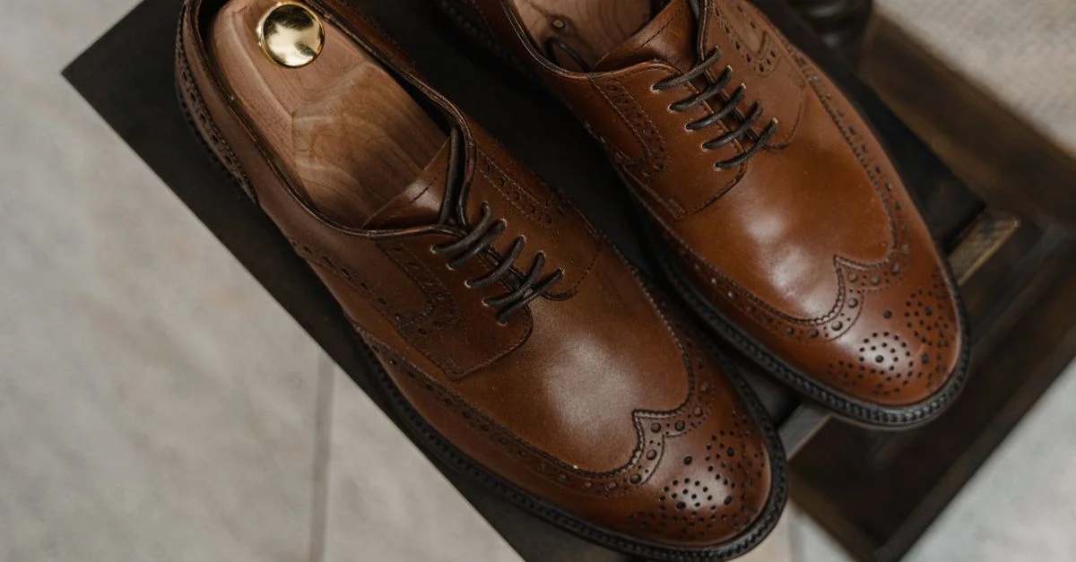 Acercamiento de lujosos zapatos Oxford de cuero marrón con diseño perforado.